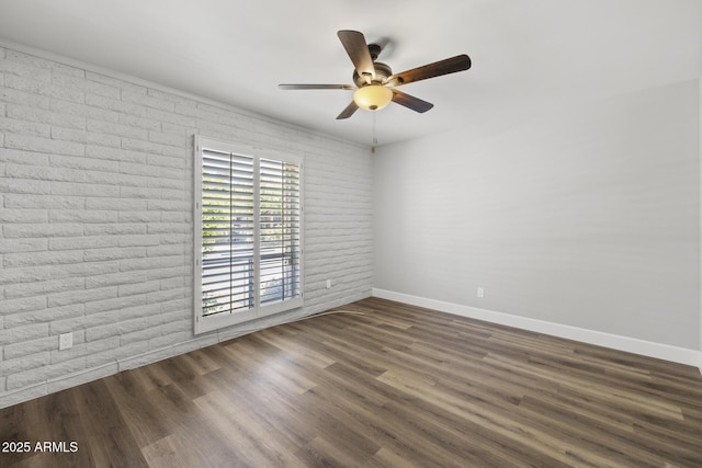 empty room with dark wood-type flooring, ceiling fan, and brick wall