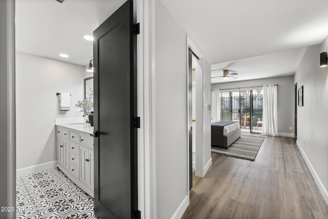 corridor with light hardwood / wood-style floors and sink