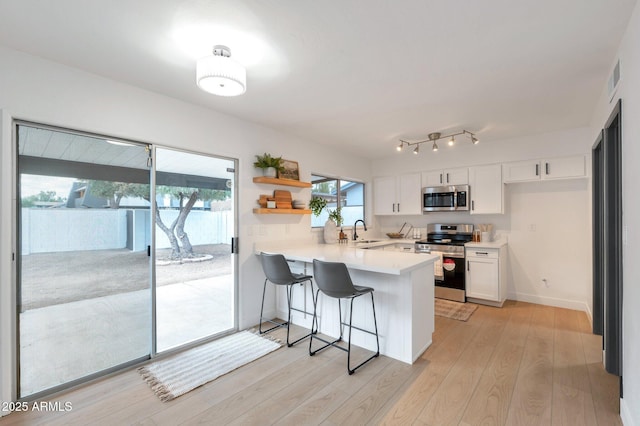 kitchen with kitchen peninsula, a breakfast bar, stainless steel appliances, sink, and white cabinetry