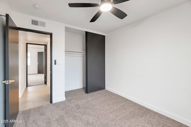 unfurnished bedroom featuring ceiling fan, a closet, and light carpet