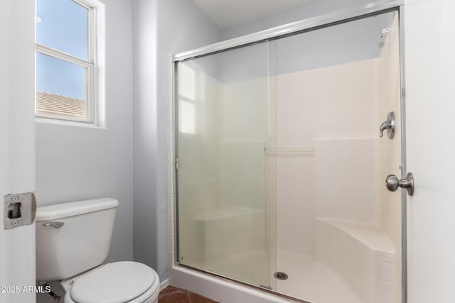 bathroom featuring a shower with door and toilet