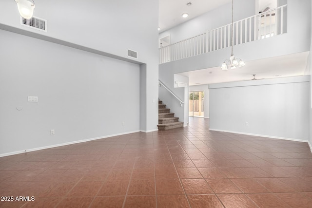 unfurnished living room featuring an inviting chandelier, dark tile patterned flooring, and a high ceiling