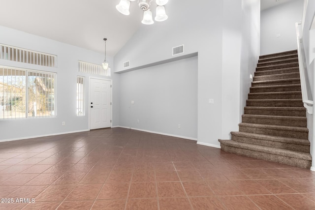 foyer featuring dark tile patterned floors, a notable chandelier, and high vaulted ceiling