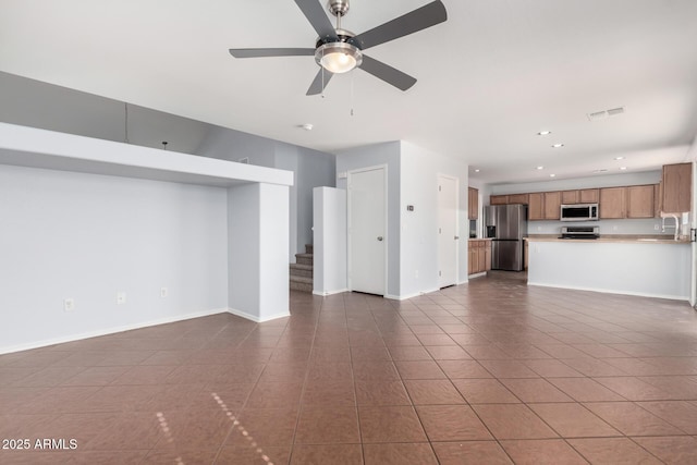 unfurnished living room featuring sink, dark tile patterned floors, and ceiling fan