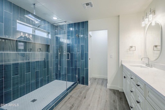 bathroom featuring an enclosed shower, vanity, and wood-type flooring