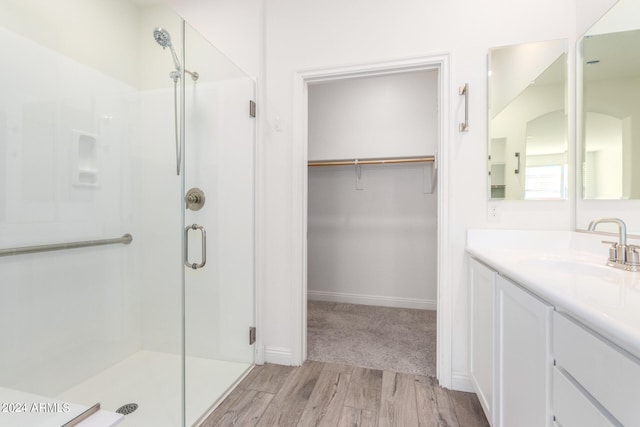 bathroom featuring vanity, wood-type flooring, and a shower with door