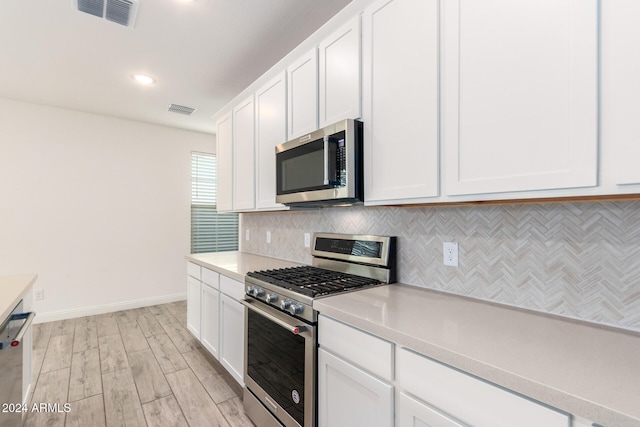 kitchen with stainless steel appliances, decorative backsplash, light hardwood / wood-style flooring, and white cabinets