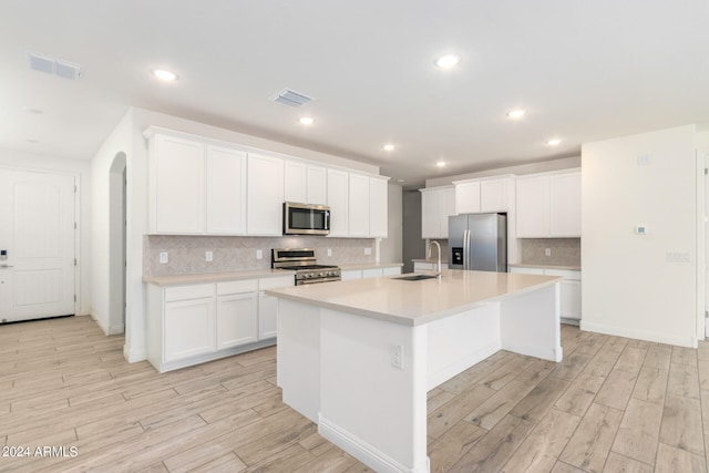 kitchen featuring appliances with stainless steel finishes, sink, an island with sink, light hardwood / wood-style floors, and white cabinets