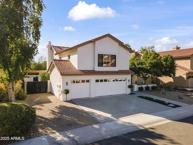 mediterranean / spanish house featuring a garage, concrete driveway, a tiled roof, fence, and stucco siding