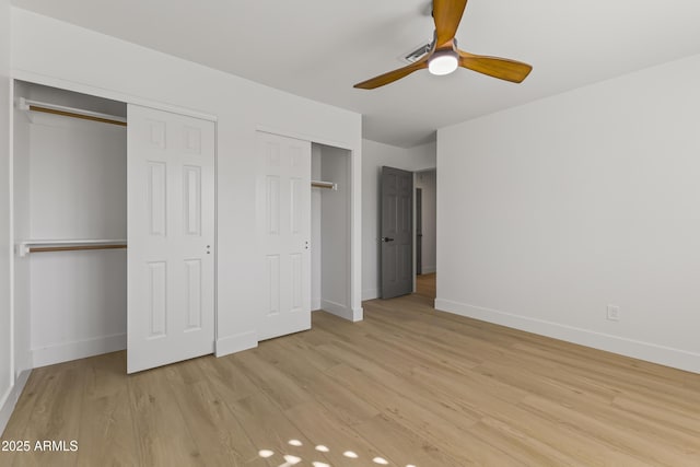 unfurnished bedroom featuring light wood-style floors, ceiling fan, baseboards, and two closets