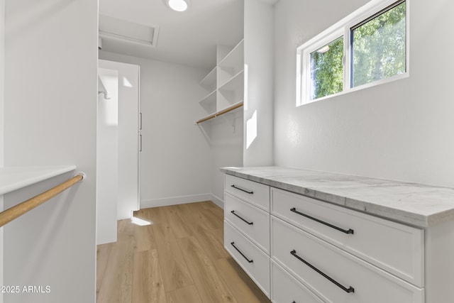 spacious closet with light wood-type flooring and attic access