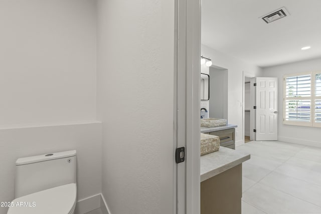 bathroom with toilet, vanity, visible vents, and baseboards