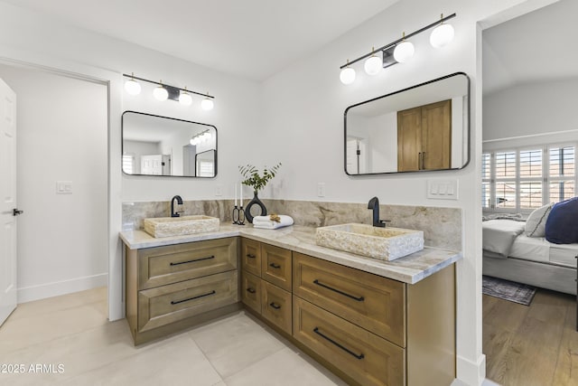 ensuite bathroom with connected bathroom, tile patterned floors, a sink, and double vanity