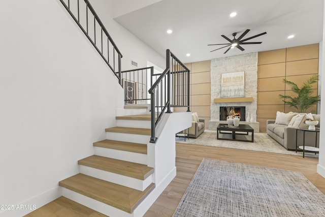 stairway with baseboards, ceiling fan, wood finished floors, a fireplace, and recessed lighting