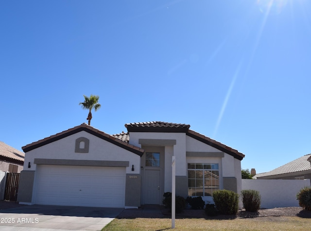 view of front of home with stucco siding, fence, a garage, driveway, and a tiled roof