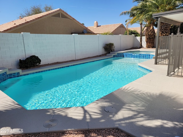 view of swimming pool with a pool with connected hot tub, a fenced backyard, and a patio