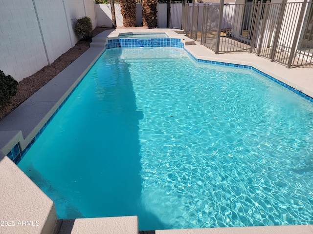 view of pool featuring a pool with connected hot tub and a fenced backyard