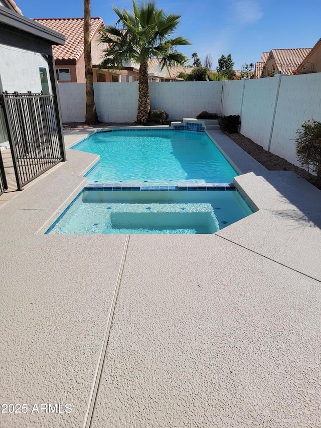 view of swimming pool featuring a fenced backyard, a pool with connected hot tub, and a patio