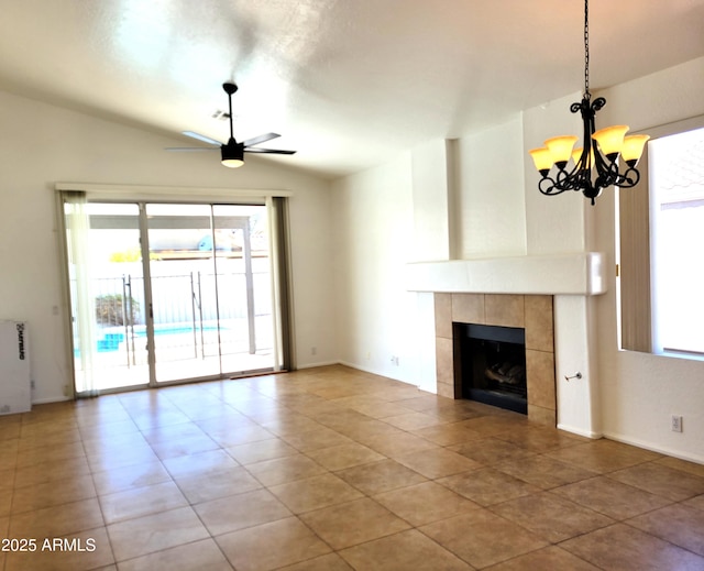 unfurnished living room featuring lofted ceiling, radiator heating unit, a tiled fireplace, and ceiling fan with notable chandelier