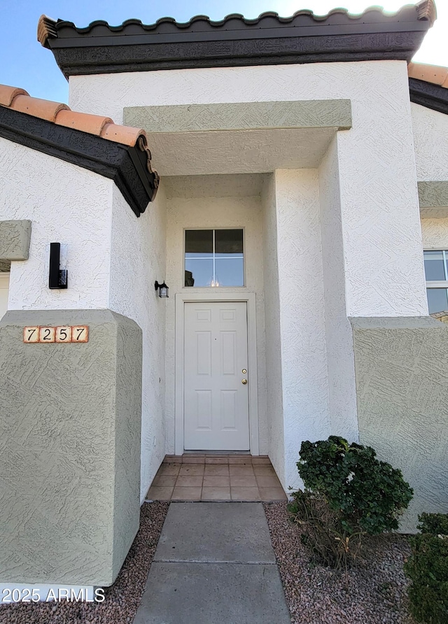 entrance to property featuring a tiled roof and stucco siding