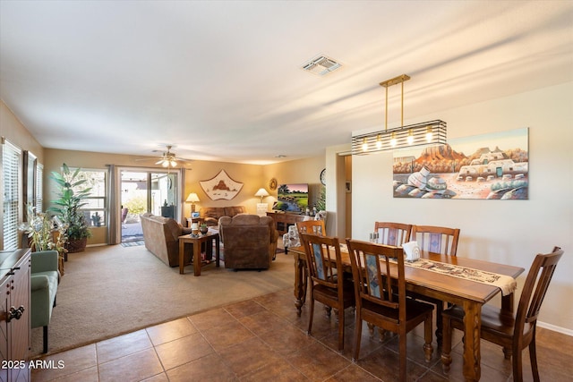 dining area with ceiling fan and dark carpet