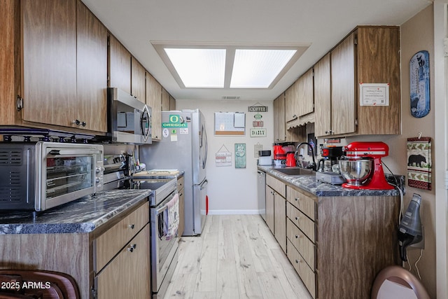 kitchen featuring sink, a skylight, light hardwood / wood-style flooring, and stainless steel appliances