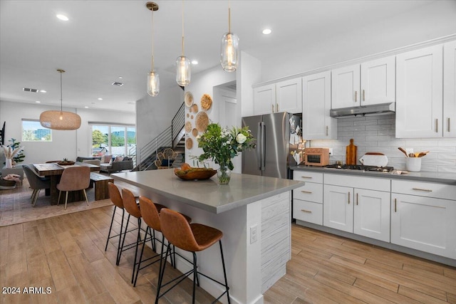 kitchen featuring appliances with stainless steel finishes, hanging light fixtures, light hardwood / wood-style floors, and white cabinetry