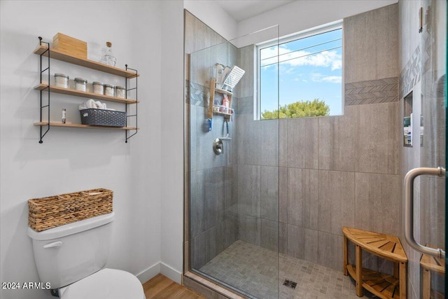 bathroom with wood-type flooring, toilet, and a shower with shower door