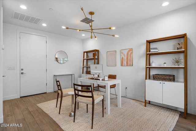 dining space with light hardwood / wood-style flooring and a chandelier