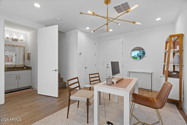 dining space with sink, light wood-type flooring, and a chandelier