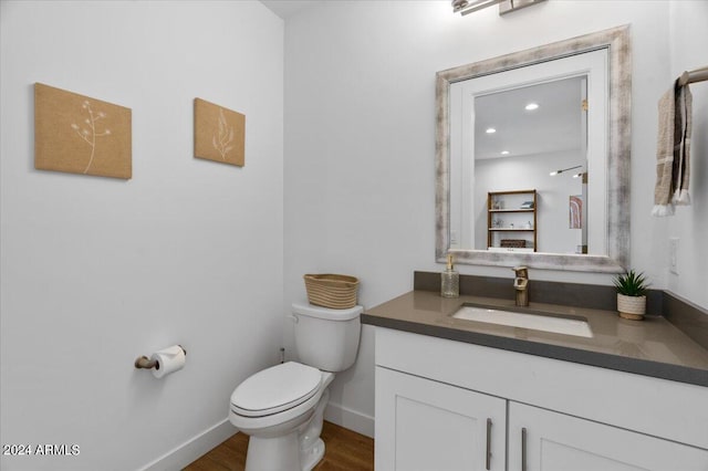 bathroom with vanity, toilet, and hardwood / wood-style flooring