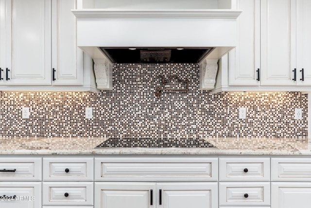 kitchen featuring light stone countertops, white cabinetry, black electric cooktop, and tasteful backsplash