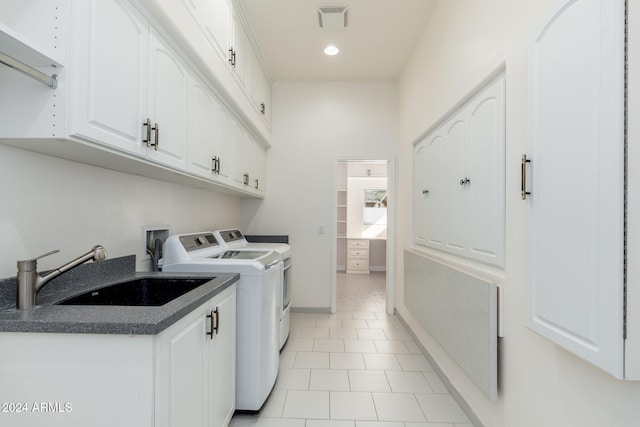 laundry area featuring washer and clothes dryer, sink, light tile patterned floors, and cabinets