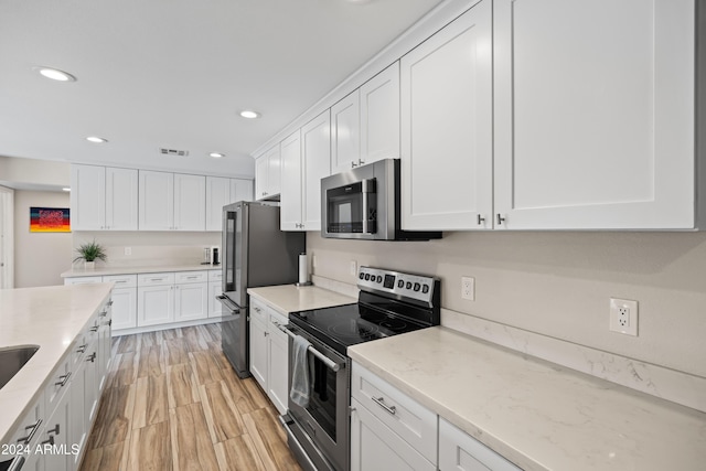 kitchen with white cabinetry, light hardwood / wood-style flooring, light stone counters, and appliances with stainless steel finishes