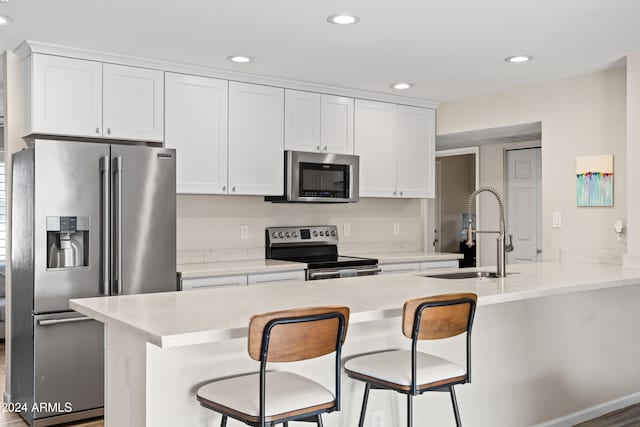 kitchen with a kitchen breakfast bar, white cabinetry, and appliances with stainless steel finishes