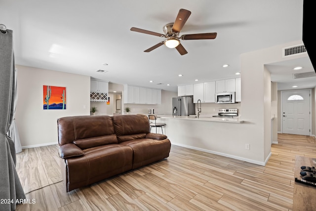 living room with ceiling fan, light wood-type flooring, and sink