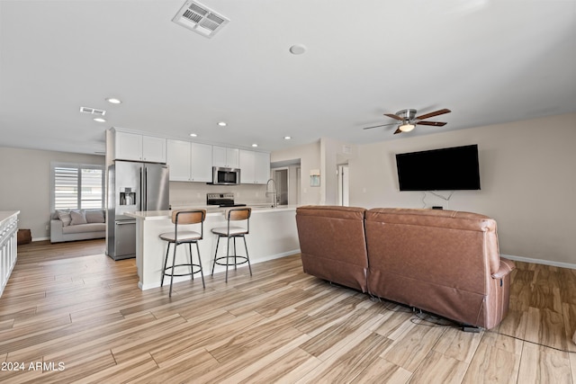 living room featuring ceiling fan, sink, and light hardwood / wood-style floors