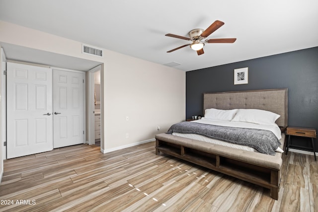 bedroom featuring connected bathroom, ceiling fan, and light wood-type flooring