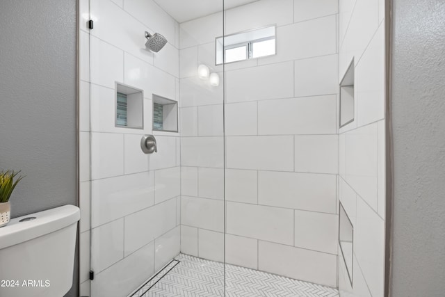 bathroom featuring tiled shower and toilet