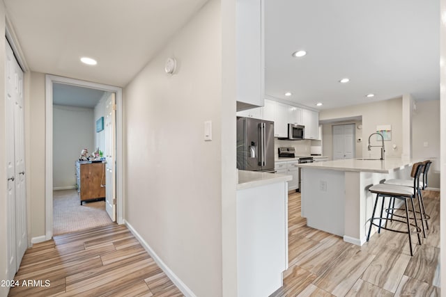 kitchen with kitchen peninsula, a breakfast bar, stainless steel appliances, sink, and white cabinetry