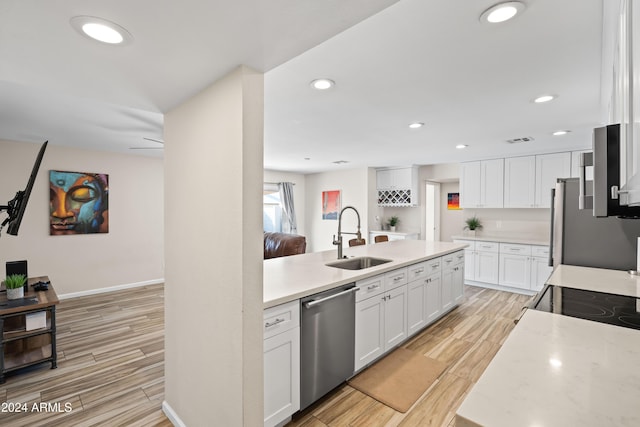 kitchen featuring light stone countertops, sink, stainless steel appliances, white cabinets, and light wood-type flooring