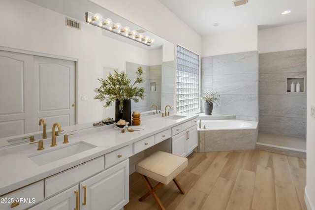 8227 E Beardsley Rd, Scottsdale, AZ 85255 - bathroom with visible vents, a sink, double vanity, wood finished floors, and a garden tub
