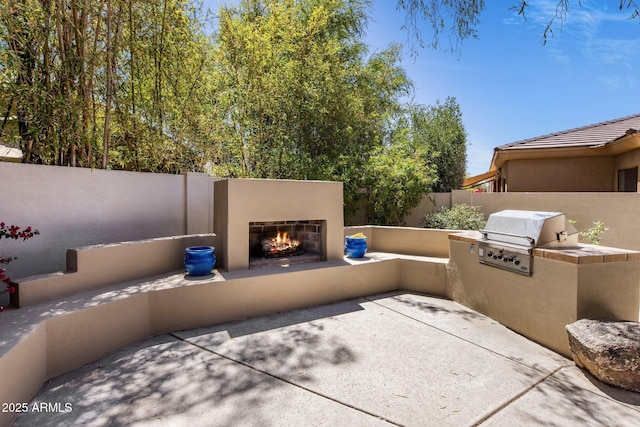 8227 E Beardsley Rd, Scottsdale, AZ 85255 - view of patio featuring an outdoor kitchen, a fenced backyard, a grill, and a lit fireplace
