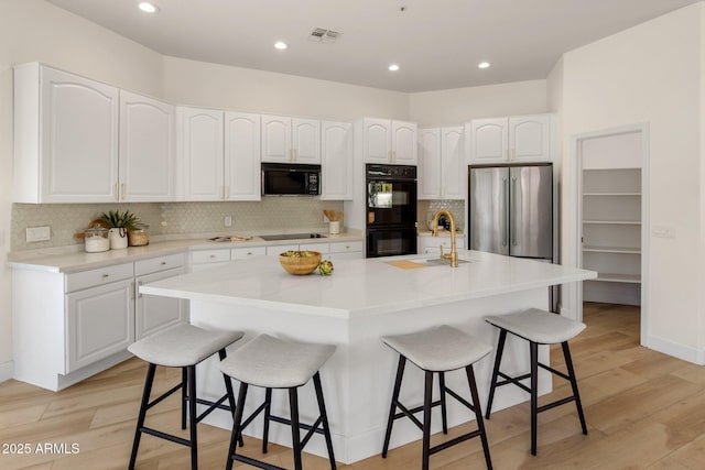 8227 E Beardsley Rd, Scottsdale, AZ 85255 - kitchen featuring tasteful backsplash, visible vents, a sink, a kitchen bar, and black appliances