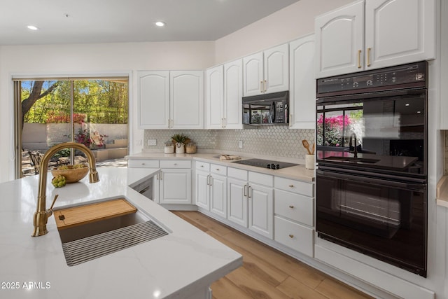 8227 E Beardsley Rd, Scottsdale, AZ 85255 - kitchen with light wood-type flooring, white cabinetry, black appliances, a sink, and decorative backsplash