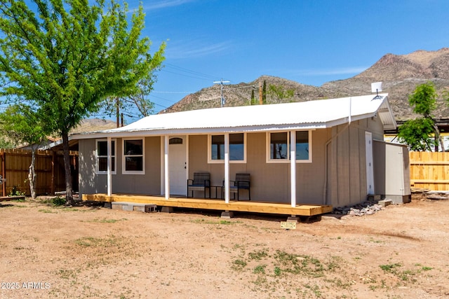 rear view of property with metal roof, a deck with mountain view, and fence