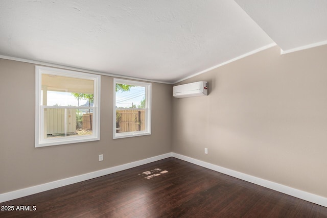 empty room with a wall mounted AC, baseboards, ornamental molding, and dark wood-style floors