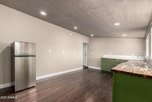 kitchen featuring dark wood-style floors, a sink, freestanding refrigerator, green cabinets, and wood counters