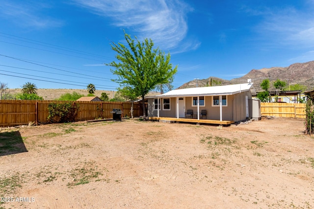 rear view of house featuring a fenced backyard and a deck with mountain view