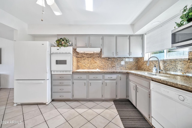 kitchen featuring white appliances, backsplash, sink, ceiling fan, and light tile patterned flooring